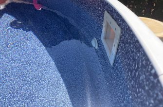 Close-up of a blue speckled pool/hot tub interior with a white edge and recessed maintenance panel