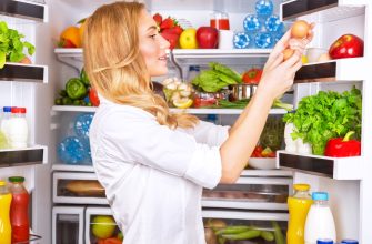 Woman placing eggs in a fully stocked refrigerator, surrounded by fresh produce and drinks.