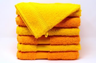 Stack of fluffy yellow and orange towels folded neatly, with a yellow towel draped over the top surface.