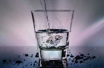 A glass of water with a diamond submerged inside, water splashing as it is poured into the glass.