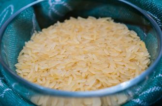 Uncooked long-grain rice in a metal bowl lined with teal fabric behind it.