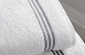 White fluffy bath towels folded, featuring a gray striped border.