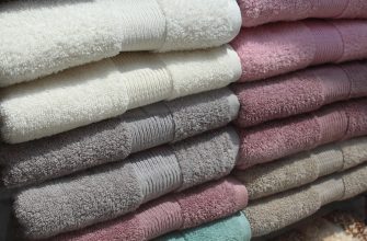 Stack of folded fluffy towels in cream, beige, gray, pink, and turquoise colors.