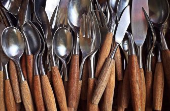 Dense jumble of metal spoons and forks with wooden handles in close-up view.