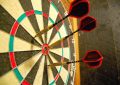 Close-up of a dartboard with three darts embedded near the bullseye.