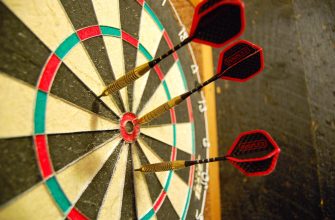 Close-up of a dartboard with three darts embedded near the bullseye.