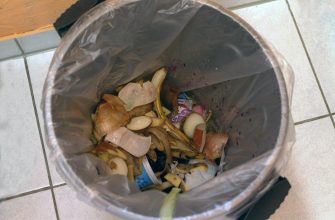 Trash can with banana peels, onion skins, and other food scraps inside a gray bag.