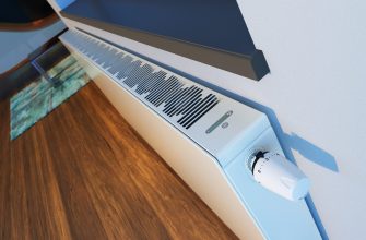 Baseboard heater with vent grille and a round thermostat knob mounted along a wall above a wooden floor; green indicator lights are on.